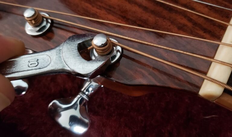 Guitar tuning machines being tightened with wrench