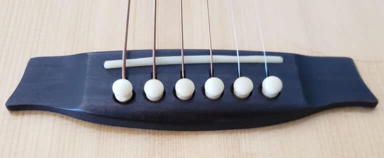 Close up view of an acoustic guitar bridge and saddle